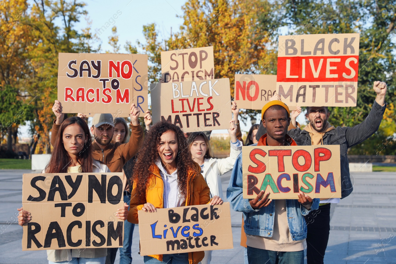 Photo of Protesters demonstrating different anti racism slogans outdoors. People holding signs with phrases