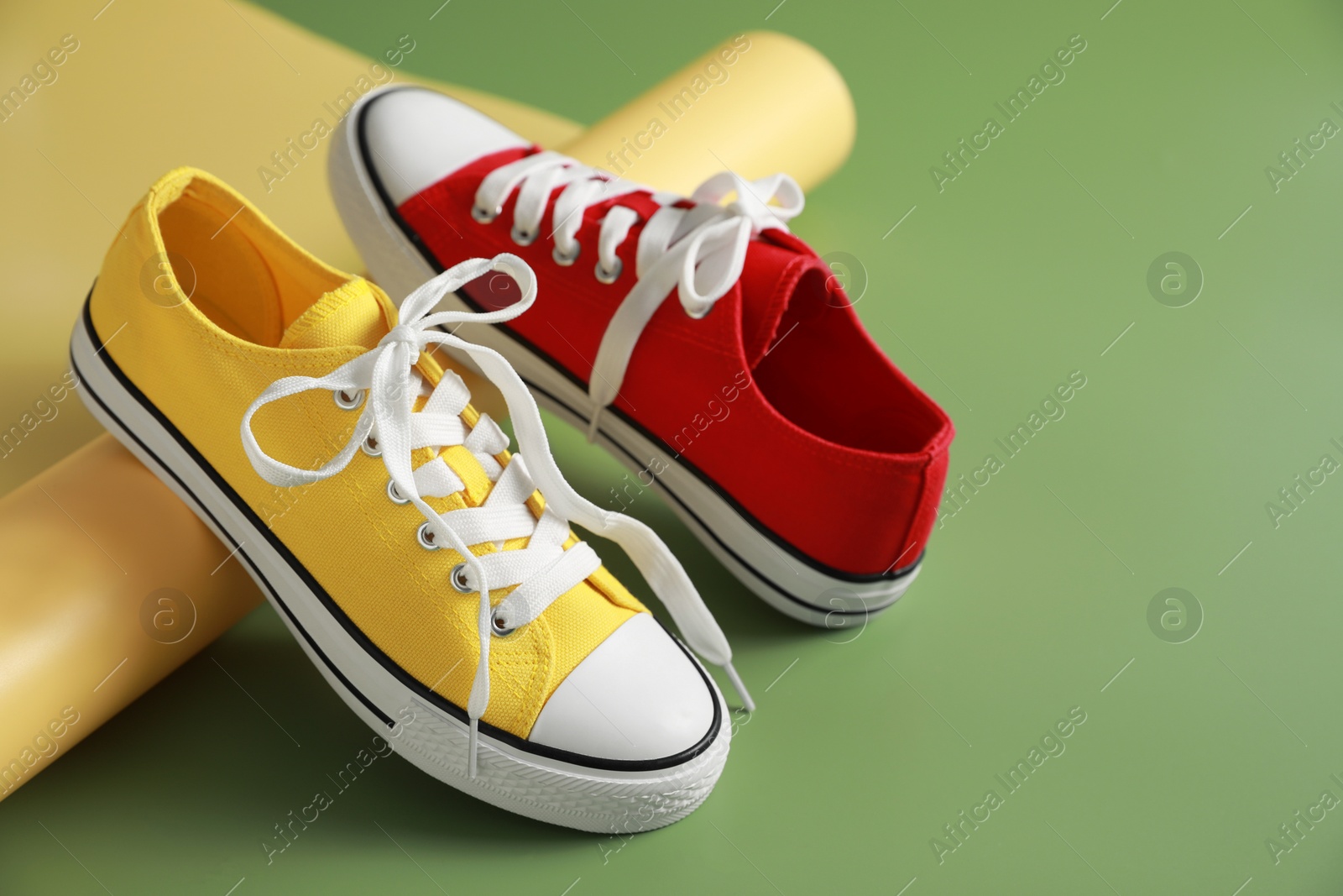 Photo of Stylish presentation of red and yellow classic old school sneakers on green background. Space for text