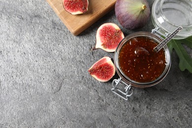 Jar of tasty sweet jam and fresh figs on grey table, flat lay. Space for text
