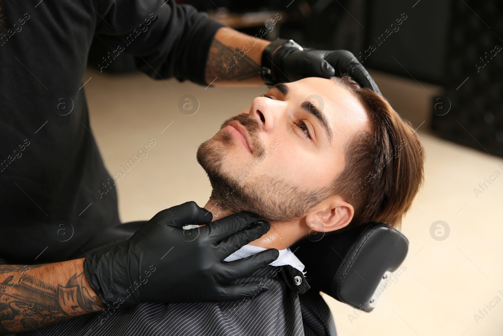 Photo of Young man visiting barbershop. Professional shaving service