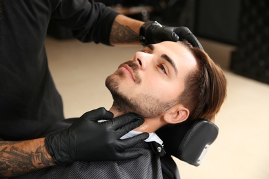 Young man visiting barbershop. Professional shaving service