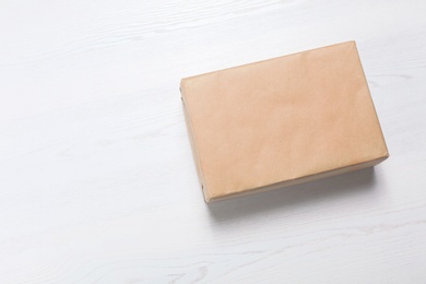 Photo of Parcel box wrapped in kraft paper on wooden background with space for text