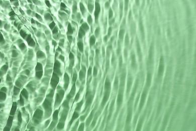 Rippled surface of clear water on green background, top view