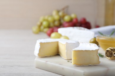 Tasty brie cheese on white wooden table, space for text