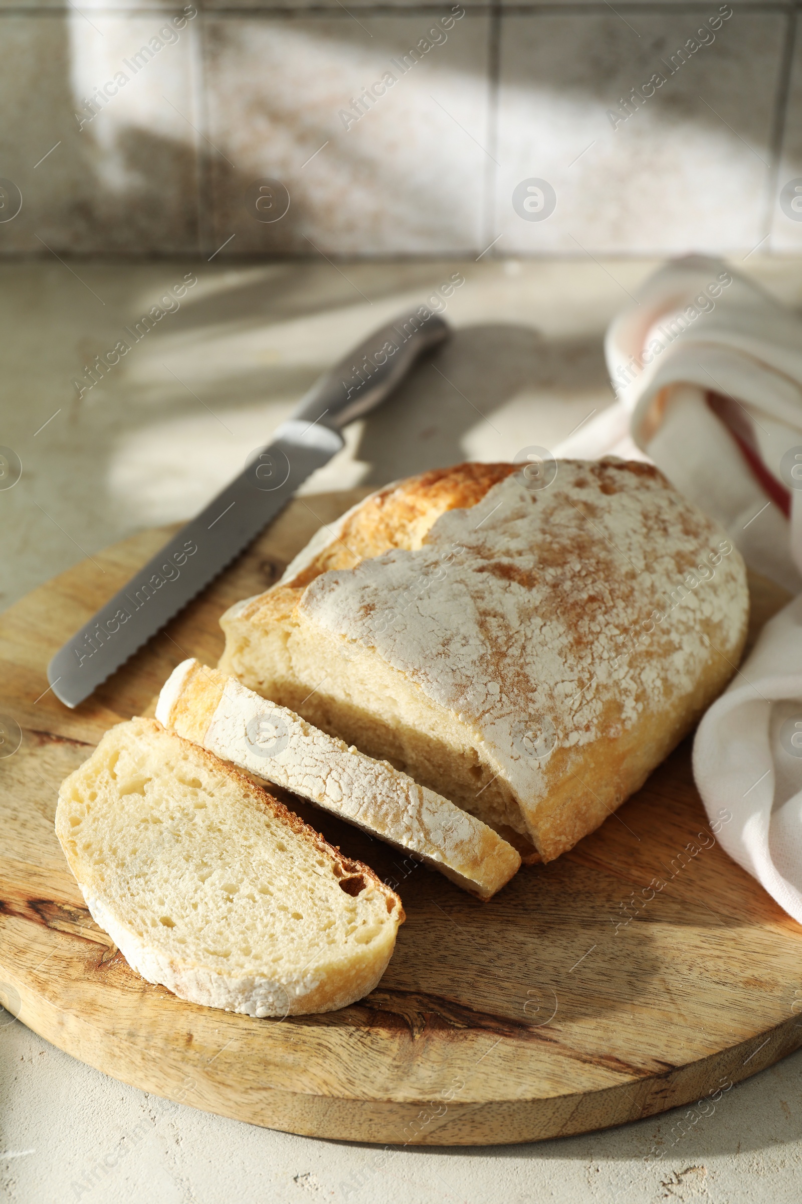 Photo of Freshly baked sourdough bread and knife on light table