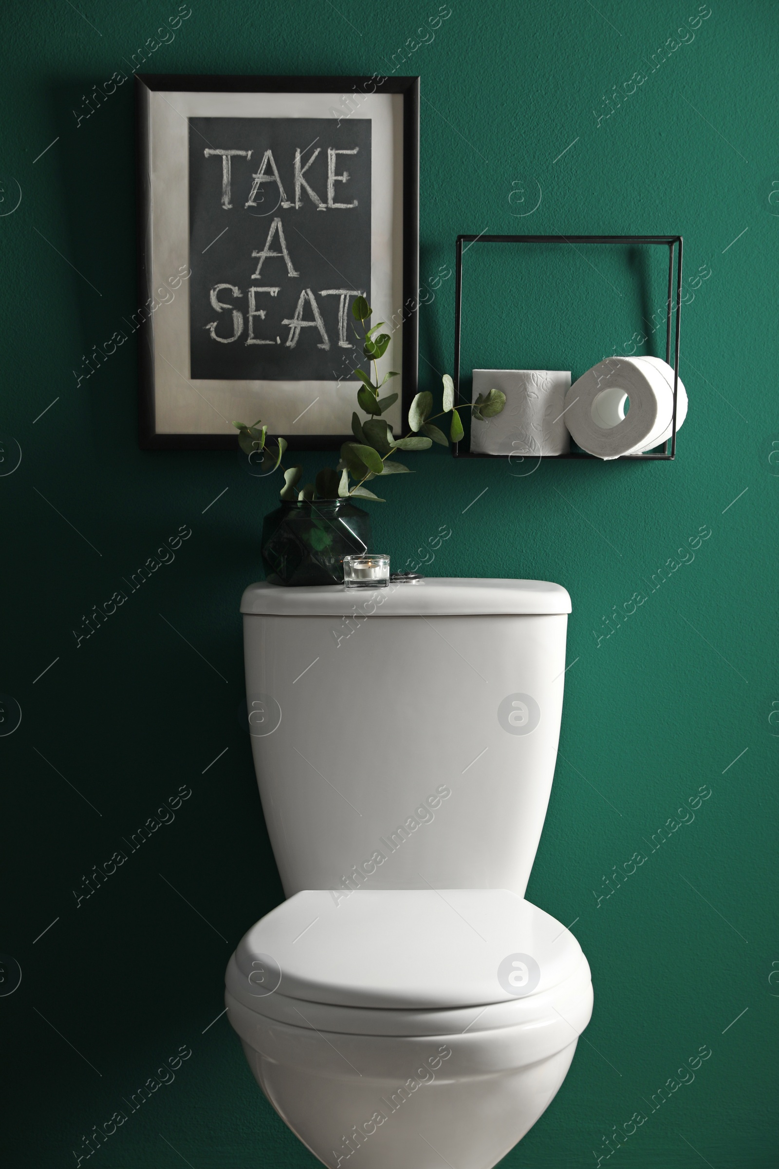 Photo of Decor elements, paper rolls and toilet bowl near green wall. Bathroom interior