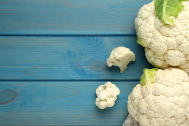 Fresh cauliflowers on light blue wooden table, top view. Space for text