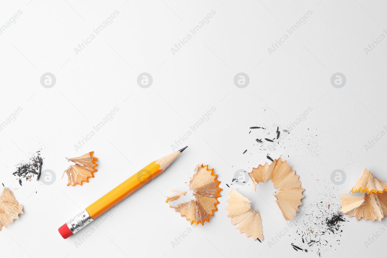 Photo of Graphite pencil and shavings on white background, flat lay. Space for text