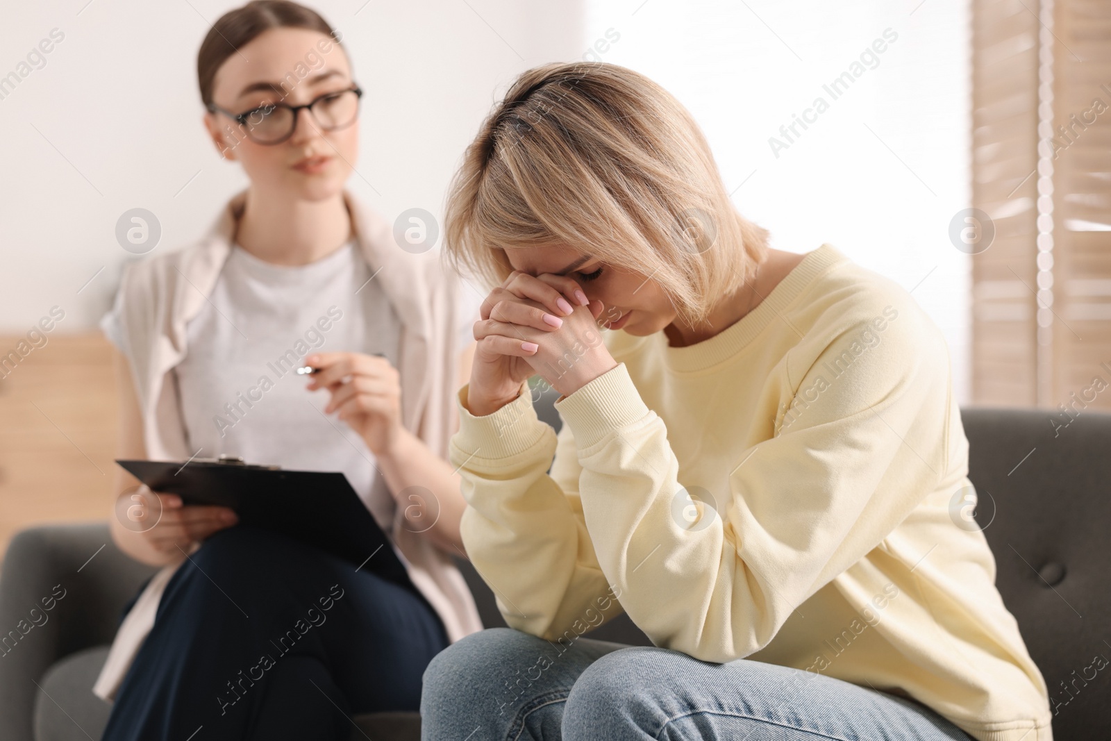 Photo of Professional psychotherapist working with on sofa patient in office