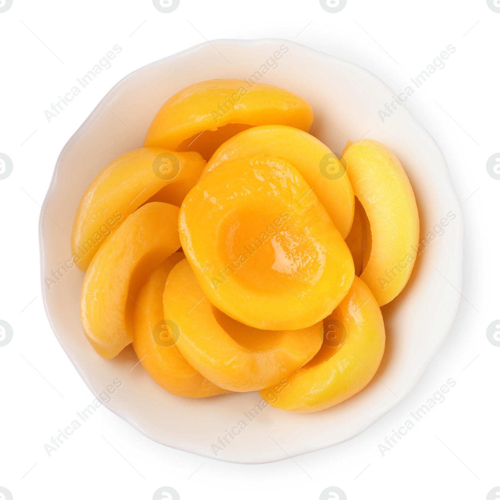 Photo of Halves of canned peaches in bowl isolated on white, top view