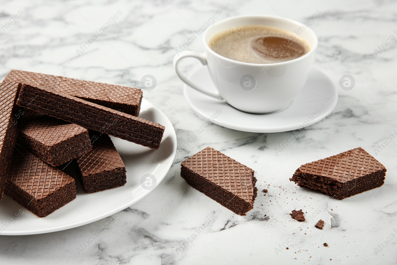 Photo of Plate of delicious chocolate wafers with cup of coffee on marble background