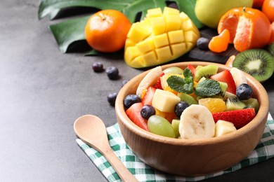 Photo of Delicious fresh fruit salad on grey table, space for text