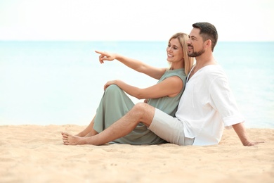 Happy romantic couple sitting together on beach