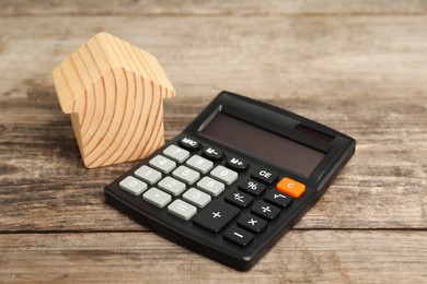 Photo of Mortgage concept. Model house and calculator on wooden table