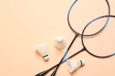 Photo of Feather badminton shuttlecocks and rackets on beige background, flat lay. Space for text