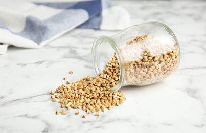 Photo of Uncooked green buckwheat grains on white marble table