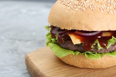 Photo of Delicious cheeseburger on grey table, closeup. Space for text