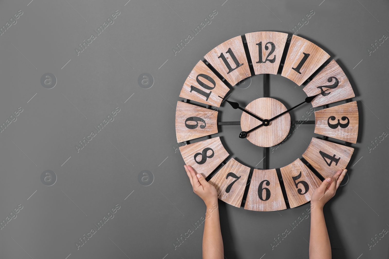 Photo of Woman holding clock near grey wall, space for text