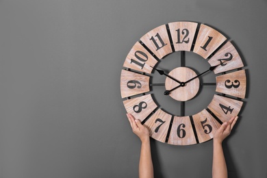 Woman holding clock near grey wall, space for text