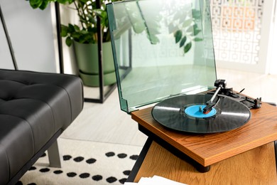 Vinyl record player on wooden table in living room