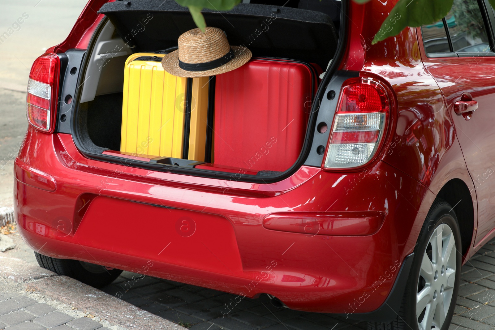 Photo of Suitcases and hat in car trunk outdoors, closeup