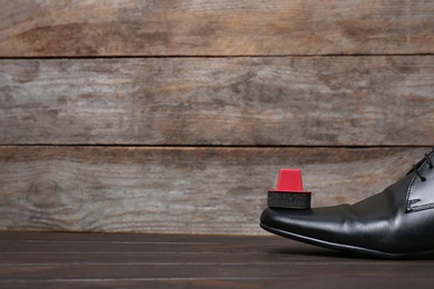 Men's leather shoes and cleaning sponge on wooden table, space for text