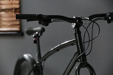 Photo of Modern black bicycle near grey wall indoors, closeup