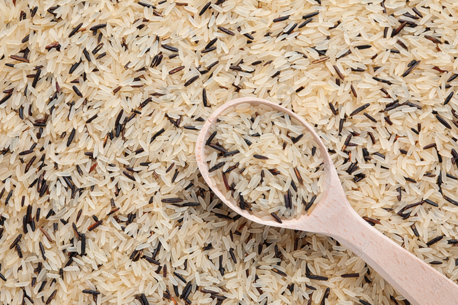 Photo of Mix of brown and polished rice with wooden spoon, top view. Space for text