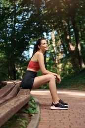 Photo of Beautiful woman in sportswear sitting on bench in park