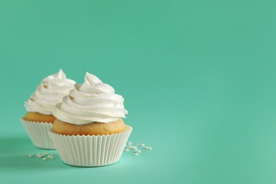 Photo of Delicious cupcakes with cream on turquoise background. Space for text