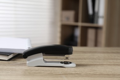 Photo of One stapler on wooden table indoors, closeup. Space for text