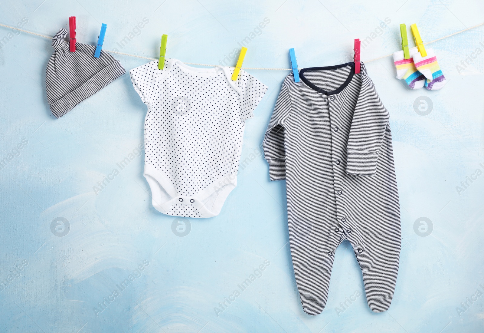 Photo of Baby clothes hanging on rope near color wall