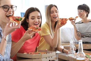 Young people having fun party with delicious pizza indoors