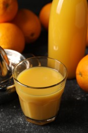 Tasty fresh oranges and juice on black table, closeup