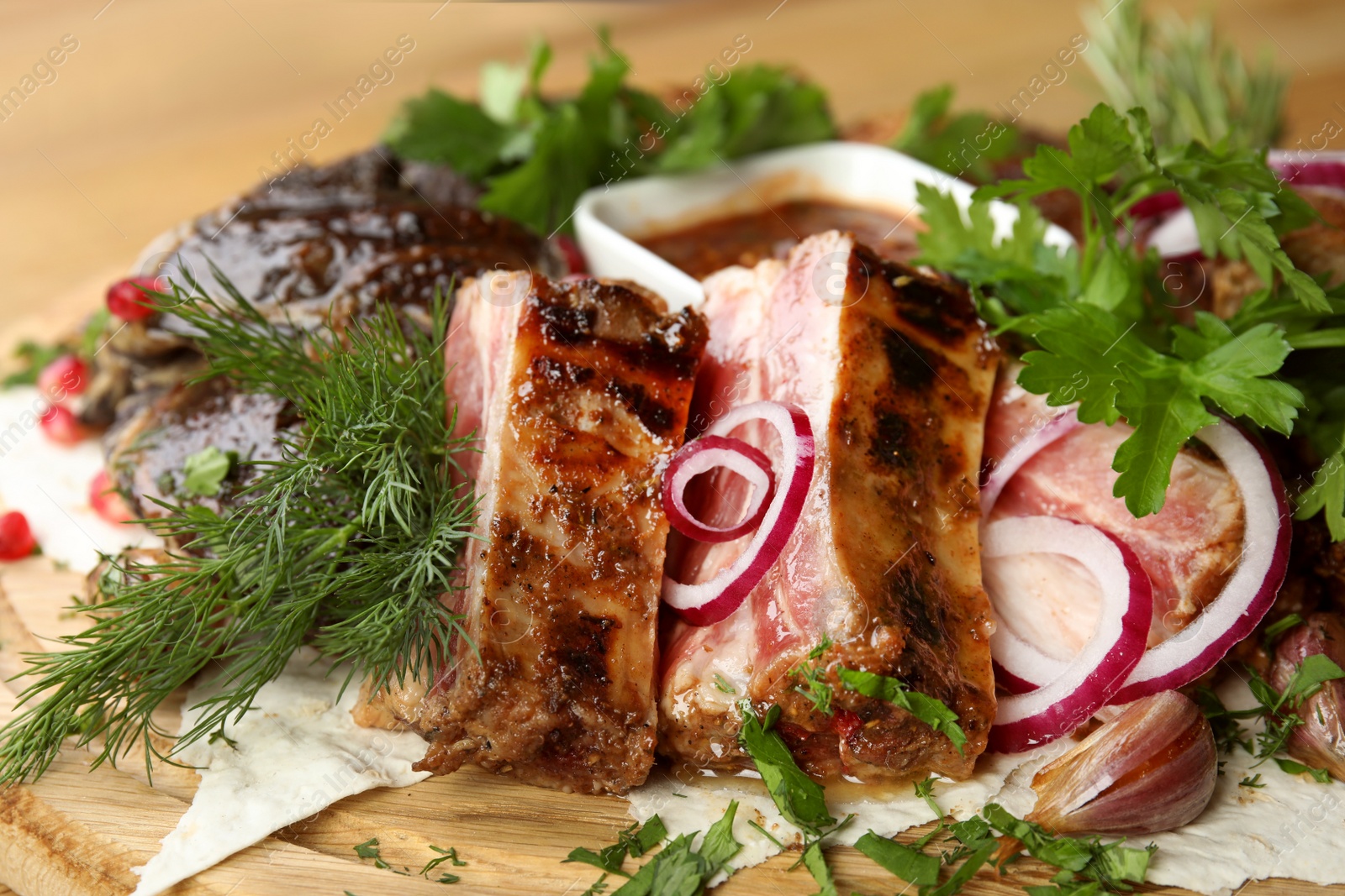 Photo of Delicious roasted meat with herbal on wooden board, closeup