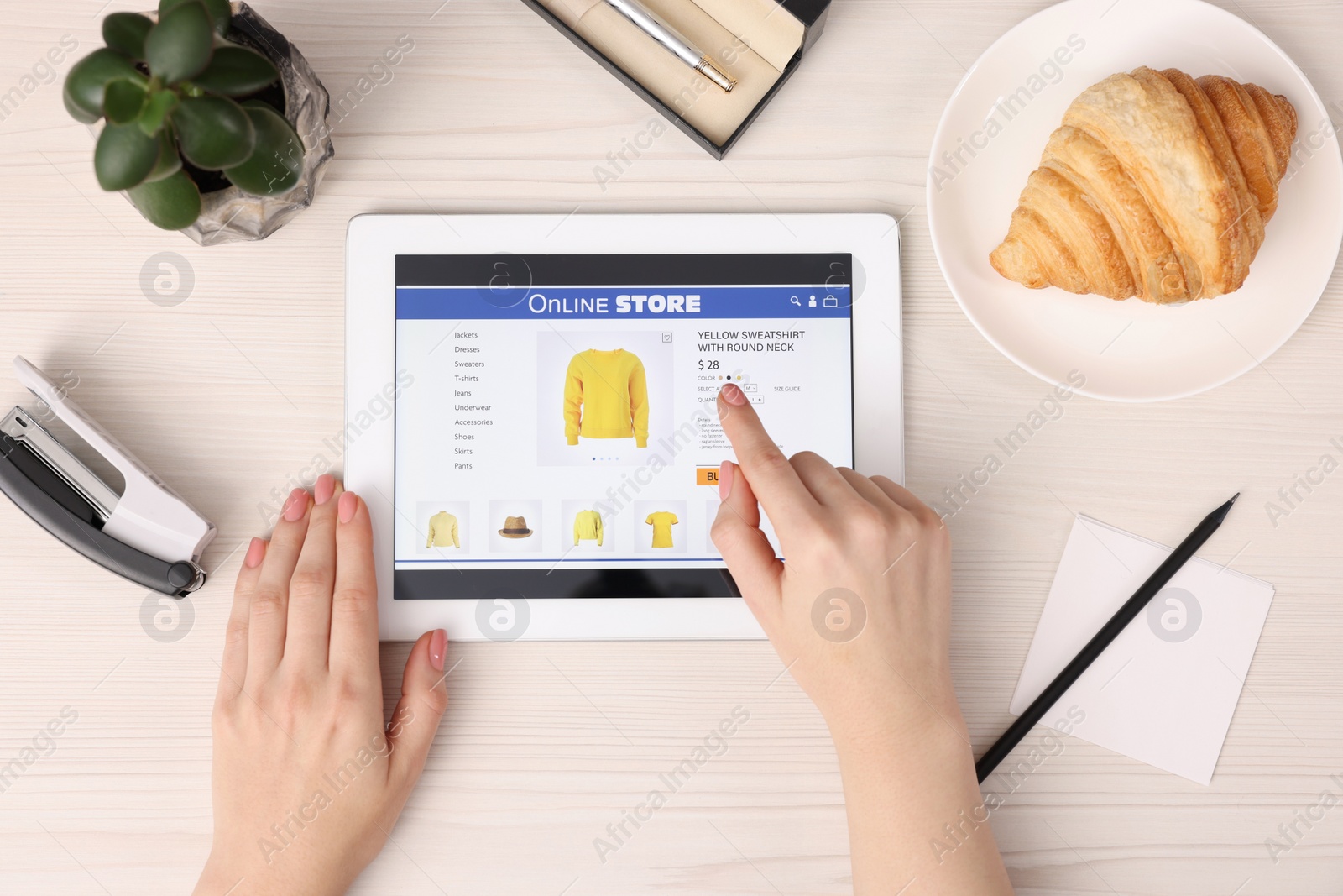 Photo of Woman with tablet shopping online at white wooden table, top view