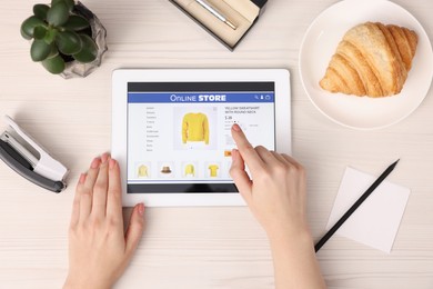 Photo of Woman with tablet shopping online at white wooden table, top view