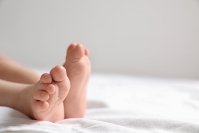 Little baby lying on bed sheet against light background, closeup. Space for text