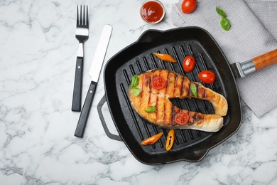 Frying pan with tasty salmon steak on light background