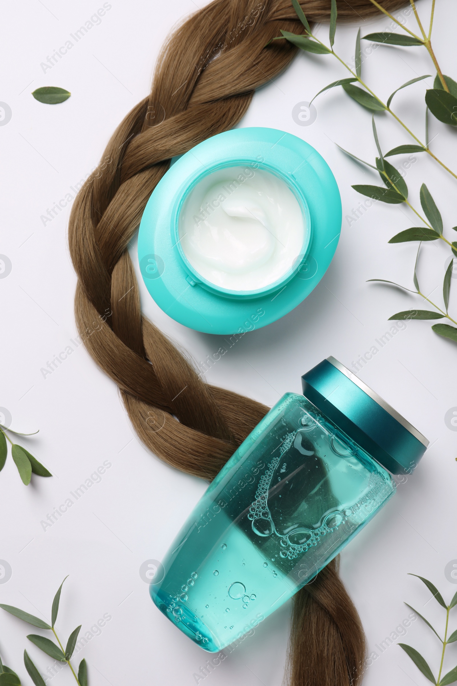 Photo of Natural cosmetic products, green leaves and hair braid on white background, flat lay