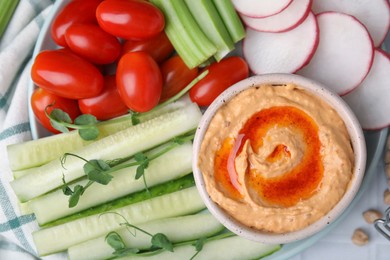 Plate with delicious hummus and fresh vegetables on table, closeup