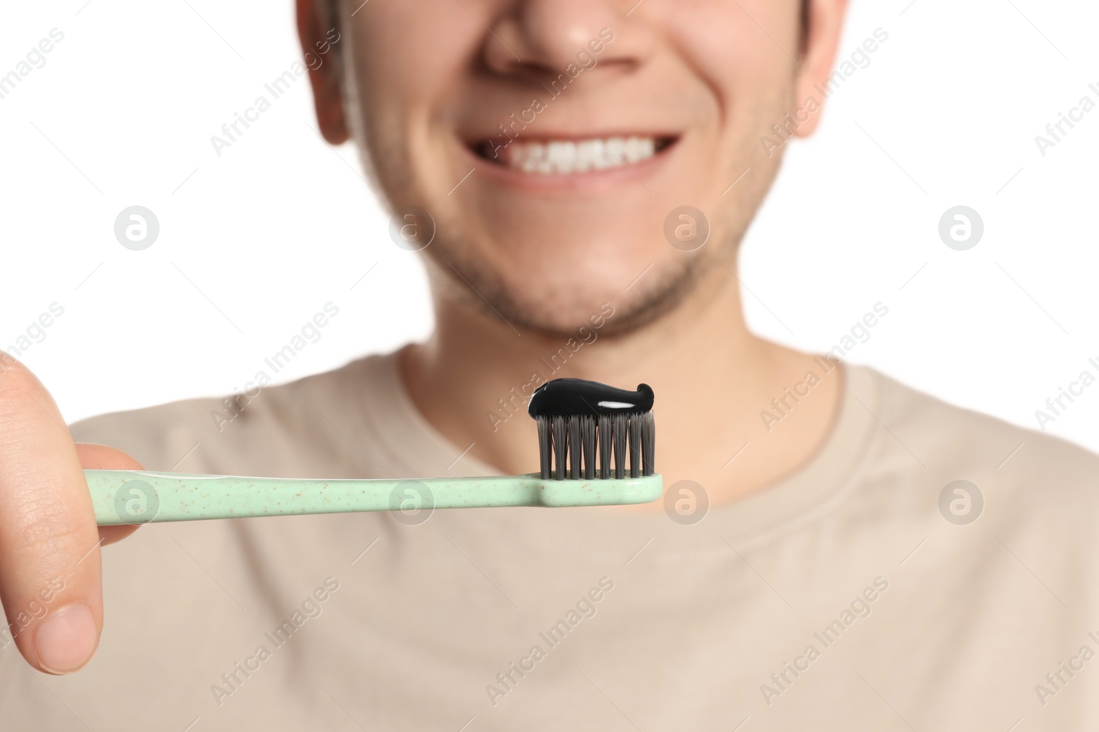 Photo of Man holding toothbrush with charcoal toothpaste on white background, closeup
