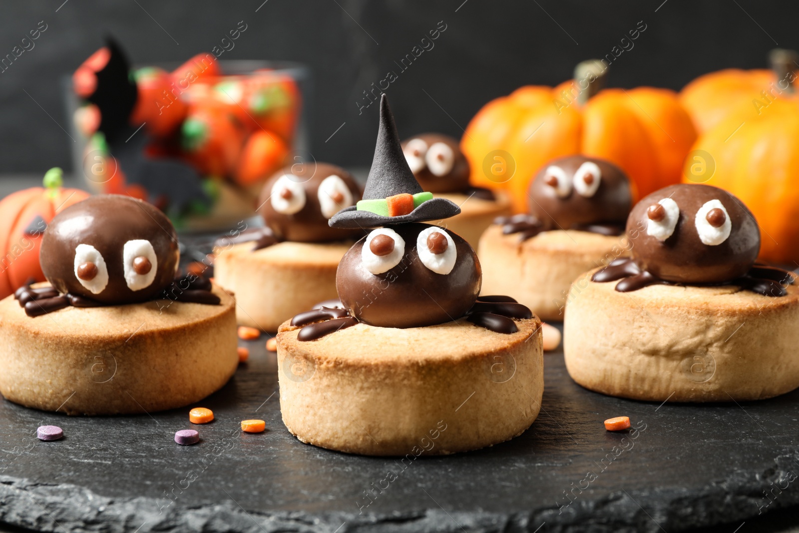 Photo of Delicious biscuits with chocolate spiders on slate plate, closeup. Halloween celebration