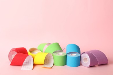 Photo of Bright kinesio tape in rolls on pink background. Space for text