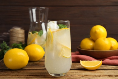 Photo of Cool freshly made lemonade and fruits on wooden table