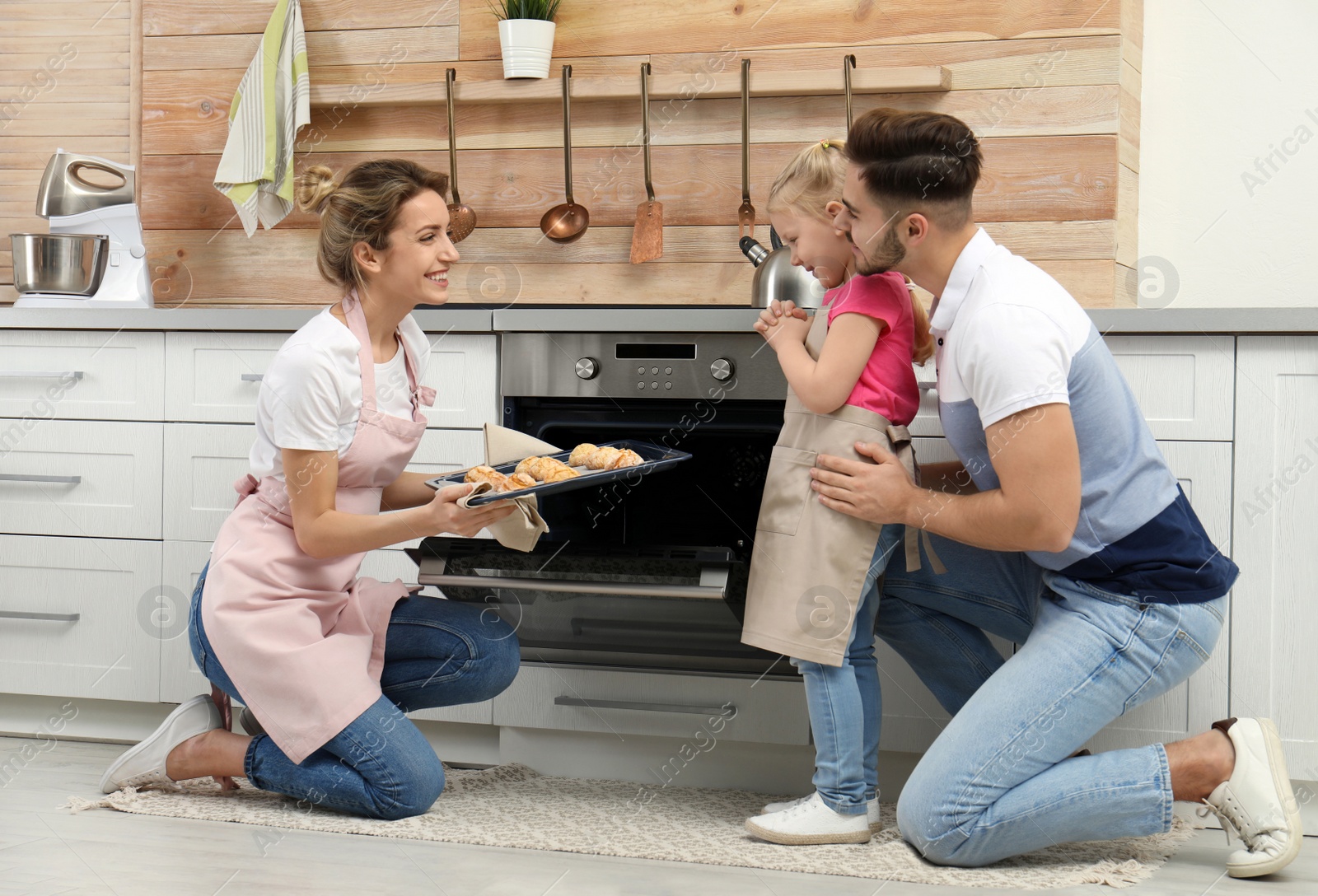 Photo of Young woman treating her family with homemade oven baked cookies in kitchen