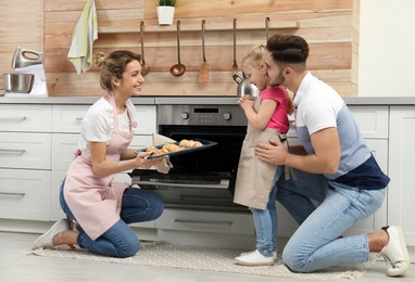 Young woman treating her family with homemade oven baked cookies in kitchen