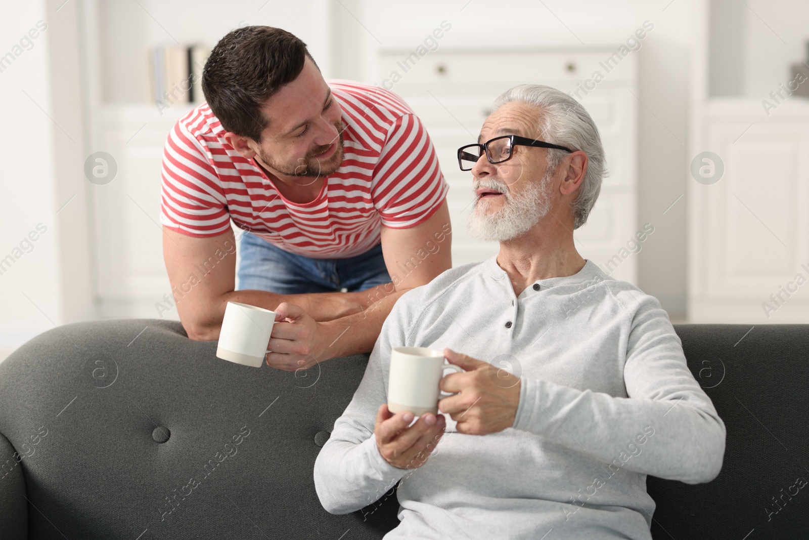 Photo of Happy son and his dad with cups at home