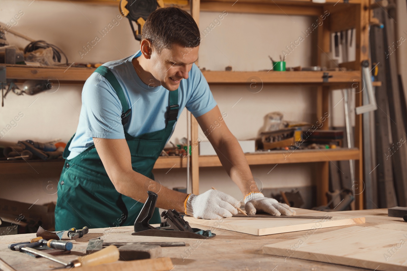 Photo of Professional carpenter measuring wooden board in workshop