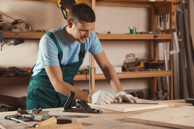 Professional carpenter measuring wooden board in workshop